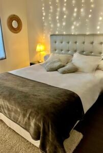 Lit double spacieux avec tête de lit aux tons minéraux et éclairage tamisé pour une nuit paisible.